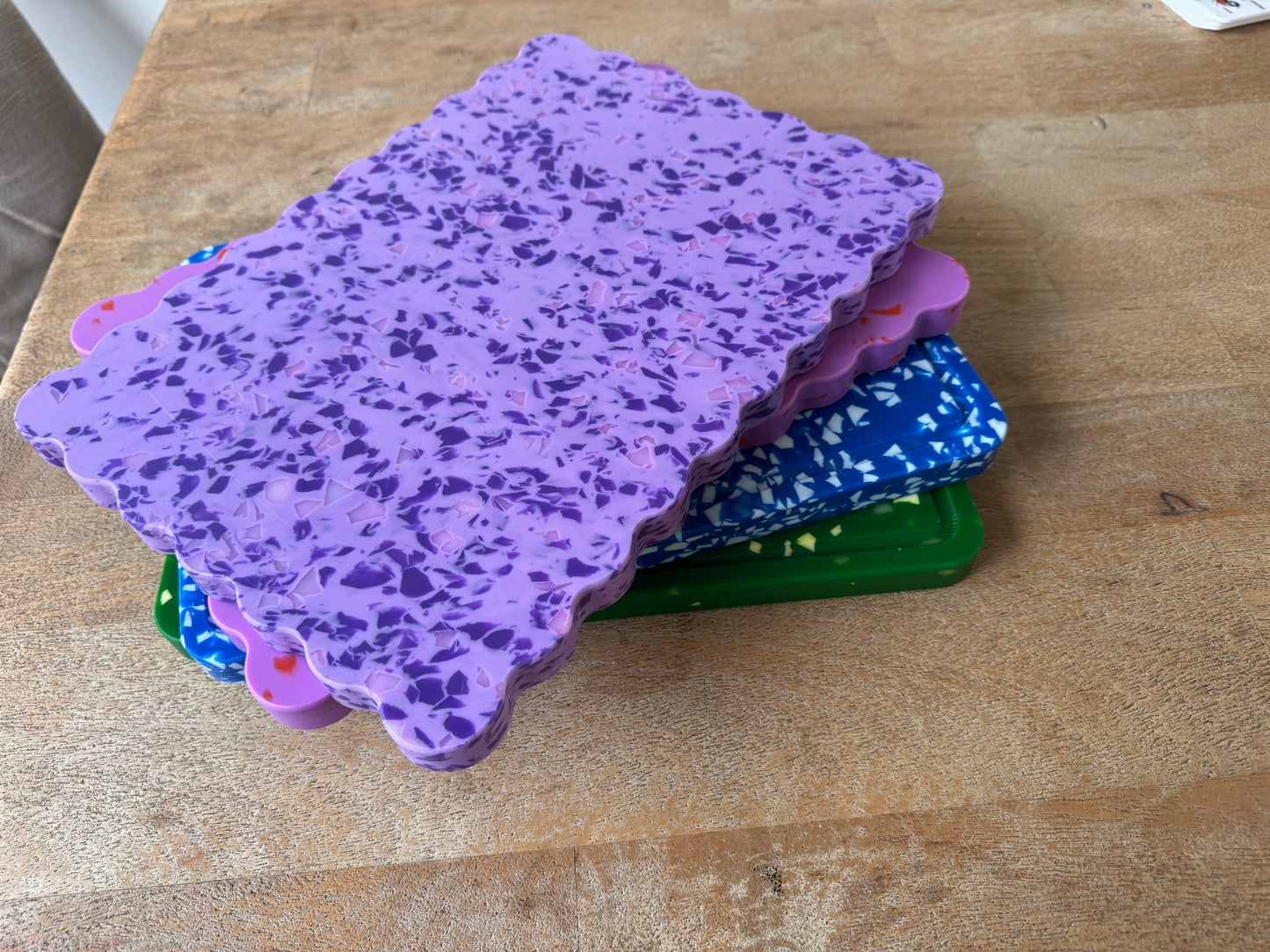 Stack of colourful plastic chopping boards on a wooden table