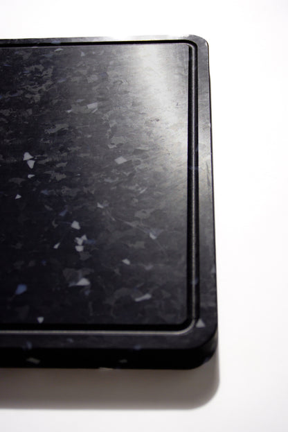 Close up black chopping board with white and grey speckles