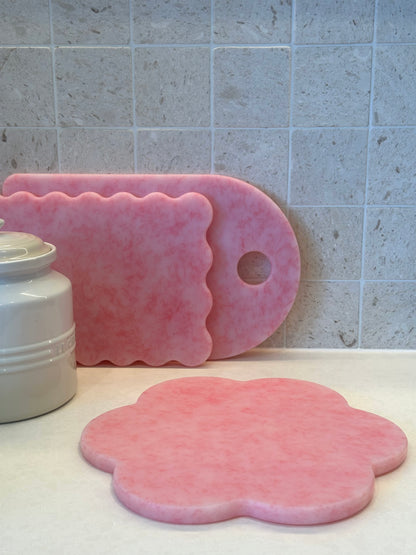 Pink flower-shaped chopping board with pink wavy and pink rectangle board in the background
