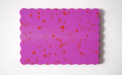 Pink wavy chopping board with orange speckles.