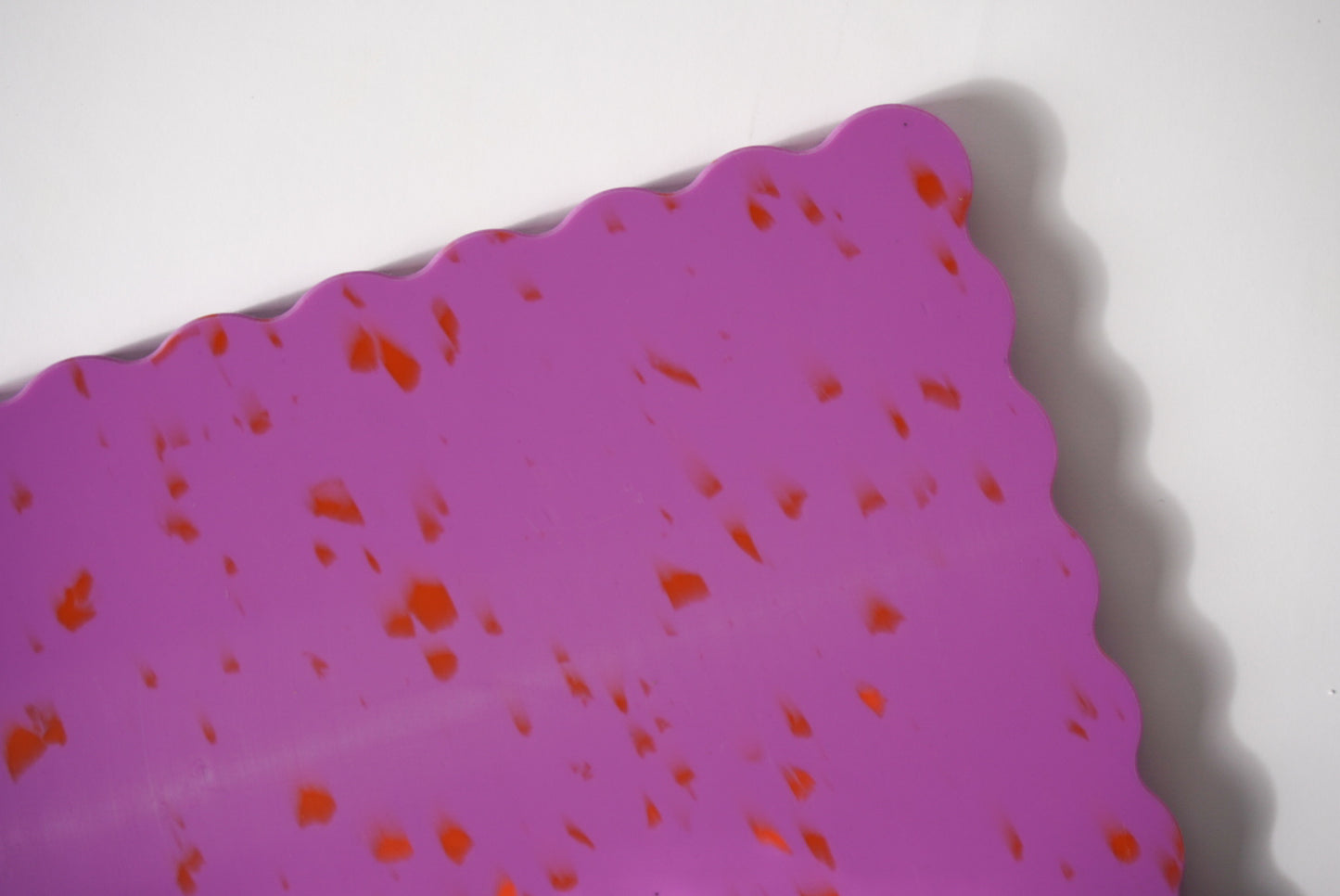 Pink wavy chopping board with orange speckles.