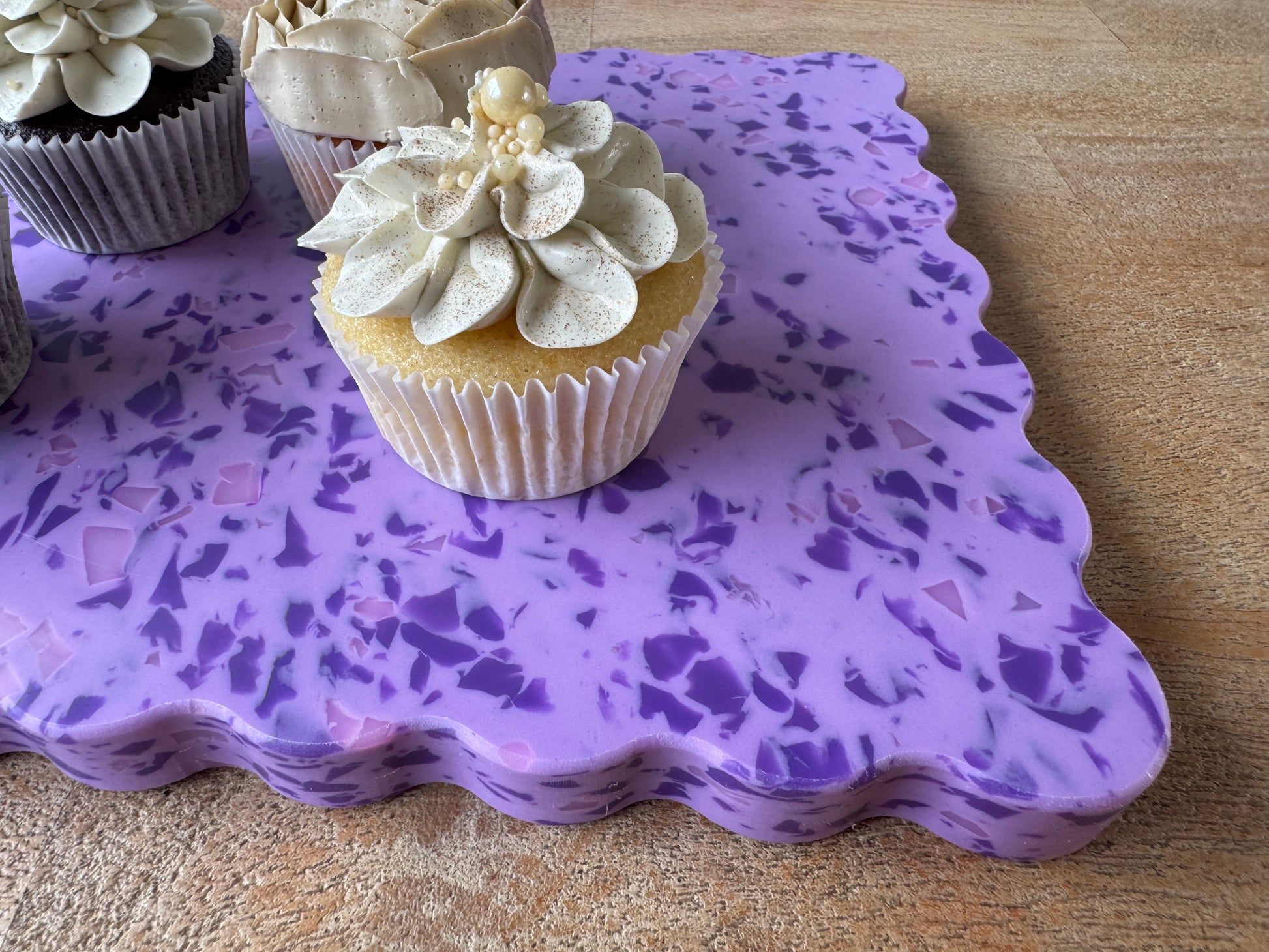 Purple speckled wavy chopping board with cupcakes