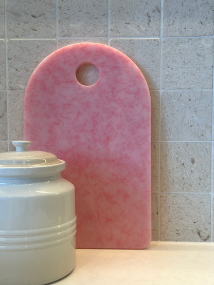 Pink chopping board with round end and hole for hanging
