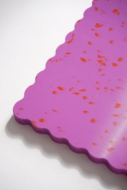 Pink wavy chopping board with orange speckles.