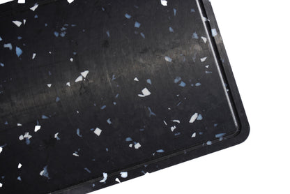 close up of black chopping board with white and grey speckles